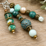 Beaded purse charm up close with turquoise, gold, and pearl beads on a wooden surface