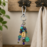 Beaded purple and turquoise purse charm hanging from a wooden hook with a beige towel.