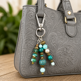 Gray textured handbag with a decorative keychain featuring beads on a wooden surface.