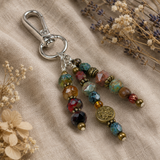 Beaded purse charm with a decorative button on a textured fabric background