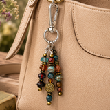 Colorful beaded purse charm attached to a beige handbag with a blurred natural background