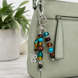Beaded keychain attached to a green handbag with a plant in the background