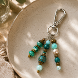 Beaded bag charm with metallic accents on a textured ceramic plate
