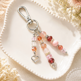 Beaded keychain with heart charm on a white dish with flowers in the background