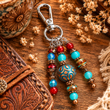 Colorful beaded purse charm with decorative elements on a wooden surface with flowers and leather item.