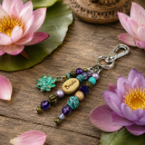 Decorative yoga handbag charm with beads and a 'Breathe' charm on a wooden surface with pink flowers.