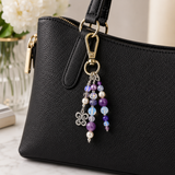 Black handbag with a decorative keychain featuring beads and a clasp.