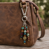 Brown leather bag with a colorful beaded keychain on a wooden surface.