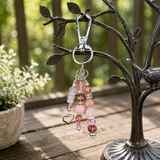 Handbag charm with beads hanging from a tree branch outdoors