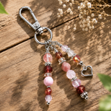 Purse Charm with beads and a heart charm on a wooden surface with dried flowers.