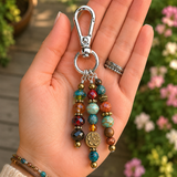 Colorful beaded purse charm held in a hand with a blurred floral background