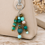 Beaded purse charm with turquoise and gold beads on a beige bag.