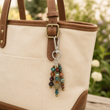 Beaded handbag charm attached to a beige handbag with a blurred natural background