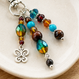 Turquoise and red butterfly bag charm with silver on a white plate