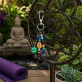 Purple and turquoise yoga beaded purse charm on a metal stand with a blurred garden background