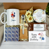 Celebrating 50 years: Personalized name mug, coffee, goodies, engraved spoon, and candle in a birthday gift basket for women.
